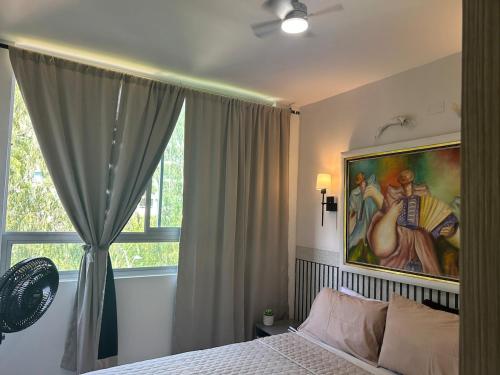 a bedroom with a painting above a bed and a window at Confortable Apartamento in Barranquilla