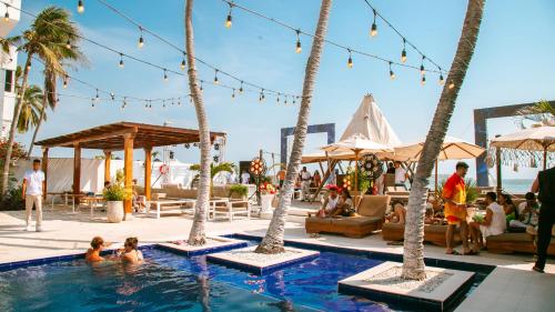 een zwembad met palmbomen en mensen in het water bij Wala Hotel and Beach Club in Cartagena