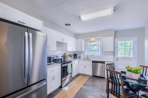 a white kitchen with a table and a refrigerator at Designer 3BR Ranch Home near Clayton & Wash U in University City