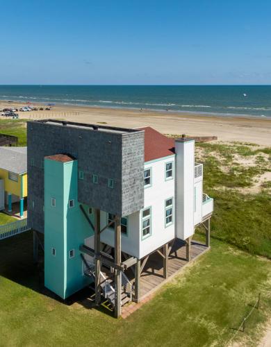 a house on the beach with the ocean behind it at Beachfront Melody in Galveston