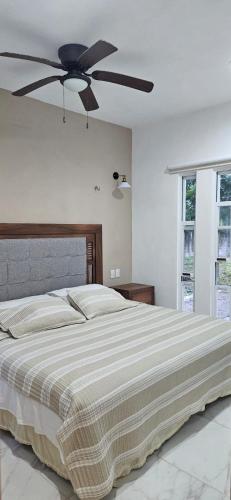 a bedroom with a large bed with a ceiling fan at Mima's Village Cozumel in Cozumel