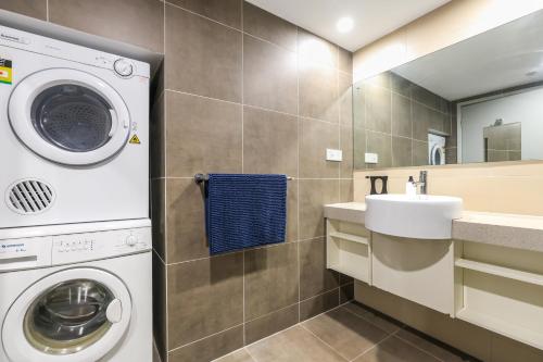 ein Badezimmer mit Waschmaschine und Waschbecken in der Unterkunft Darwin City Centre Apt 2 Bed, 2 Bath in Darwin