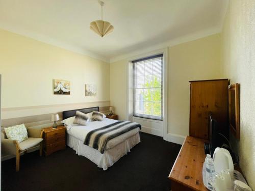 une chambre avec un lit, une chaise et une fenêtre dans l'établissement Alister Guest House, à Saint-Hélier
