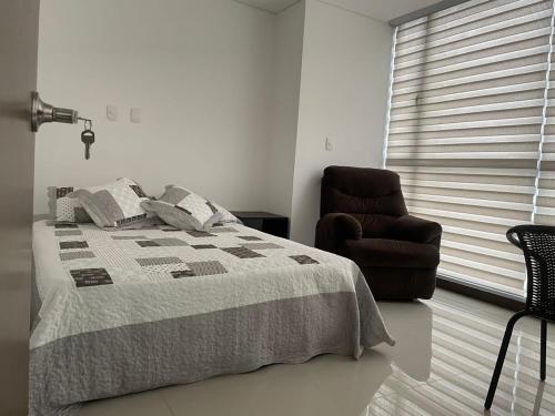 ein Schlafzimmer mit einem Bett und einem Stuhl und einem Fenster in der Unterkunft Apartamento norte de Armenia, piso 12 con zona social completa in Armenia