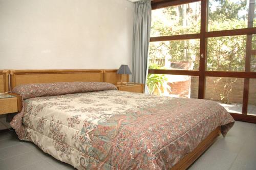 Un dormitorio con una cama y una ventana grande en Tiempo Compartido Clermont Pinamar, en Pinamar