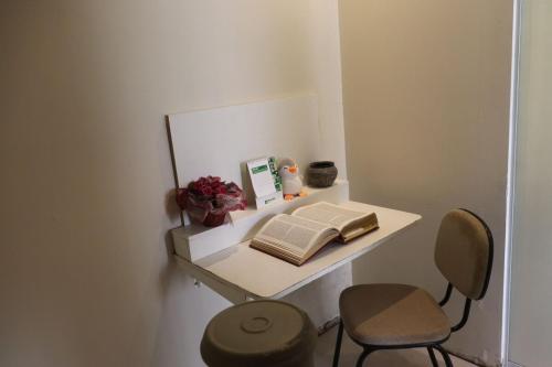 ein kleines weißes Regal mit einem Buch und zwei Stühlen in der Unterkunft São Bento Prime in São Bento do Sul