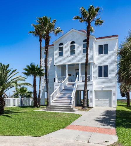 a white house with palm trees in front of it at Breakers Pointe in Galveston