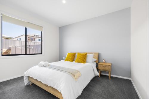 a bedroom with a bed with yellow pillows and a window at Sand and Soul with Infrared Sauna in South West Rocks