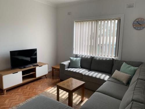 ein Wohnzimmer mit Couch und Flachbildfernseher in der Unterkunft Coconut Cottage - Sanctuary Point in Sanctuary Point