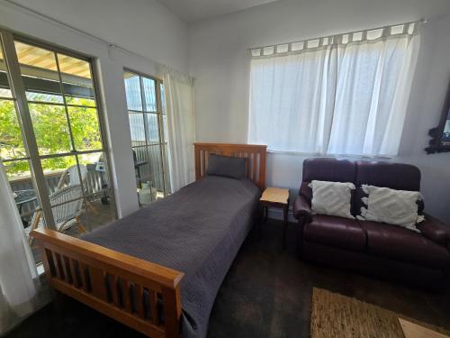 a bedroom with a bed and a couch and windows at Contemporary Studio Accommodation in Farrell Flat