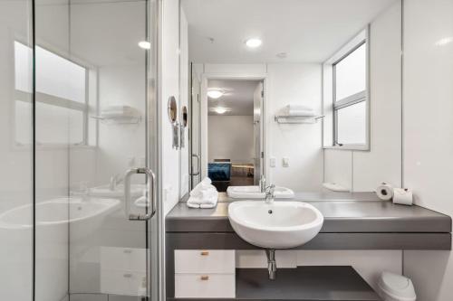 Un baño blanco con dos lavabos y una ducha. en Waterfront Queenstown Studio Peaceful Stay, en Frankton