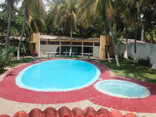 una gran piscina frente a una casa con palmeras en Hotel Rod Blue, en La Libertad