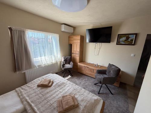 a bedroom with a bed and two chairs and a television at Bee house 12 in Odorheiu Secuiesc