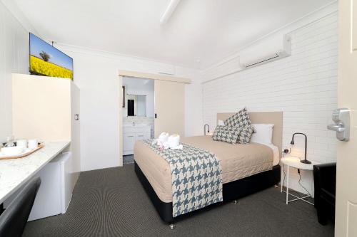 a small bedroom with a bed and a bathroom at Boggabri Motel in Boggabri