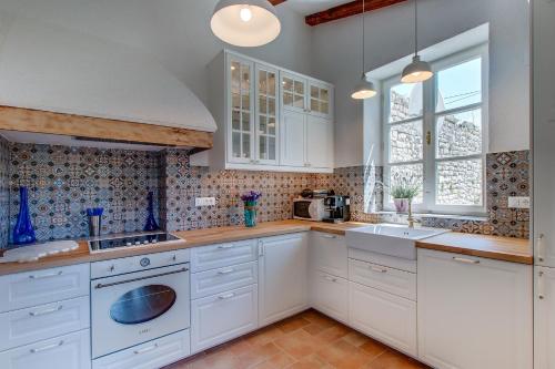 een keuken met witte kasten en een spoelbak bij Seaside house with a swimming pool Osor, Losinj - 12230 in Osor