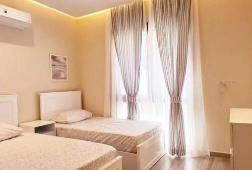 a bedroom with two beds and a window with curtains at elfaraag yyy in Jeddah