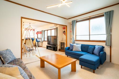 a living room with a blue couch and a table at 古民家宿 Hokusai 北斎 小樽運河5分 駅近 観光拠点 戸建貸切 in Otaru