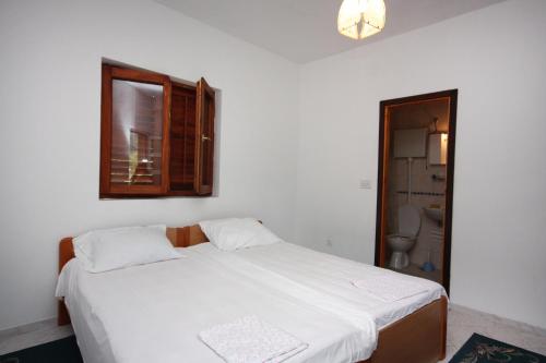una camera con letto bianco, finestra e servizi igienici di Apartments and rooms by the sea Sobra, Mljet - 4888 a Sobra