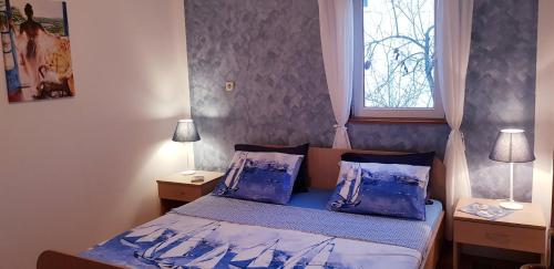 a bedroom with a bed with blue sheets and a window at Apartments by the sea Ston, Peljesac - 10226 in Mali Ston