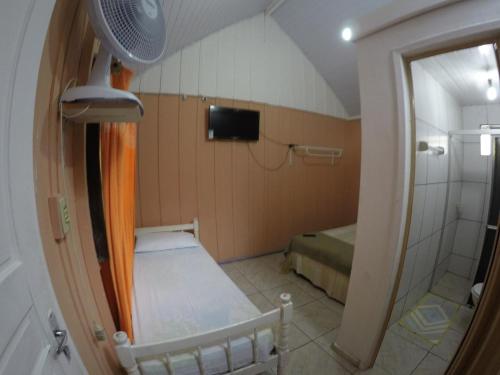 a small room with a bed and a shower at Recanto Ana Valentin in Paranaguá