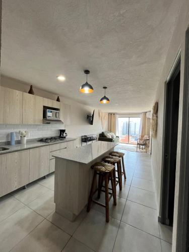 a kitchen with a counter and some stools in it at Acojedor departamento en el centro de Guadalajara in Guadalajara