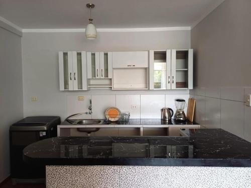 une cuisine avec des armoires blanches et un comptoir noir dans l'établissement Modern and cozy apartment, à Jaén
