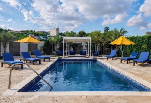 a swimming pool with blue chairs and umbrellas at Comfort Inn Tegucigalpa in Tegucigalpa