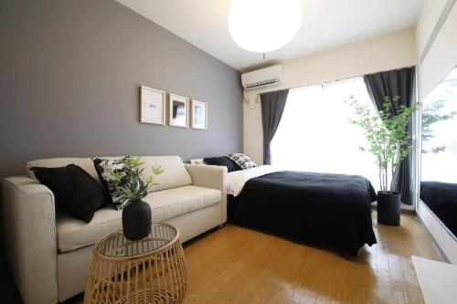 a living room with a couch and a bed at ウィズ八王子レジデンス 102 in Hachioji