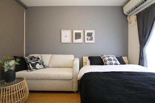 a living room with a couch and a bed at ウィズ八王子レジデンス 102 in Hachioji