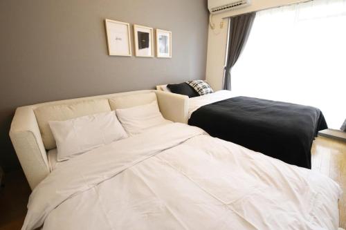 a living room with a couch and a bed at ウィズ八王子レジデンス 102 in Hachioji