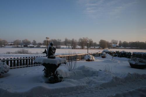 a park covered in snow with a statue and a fountain at Hotel Seeblick garni in Gartow