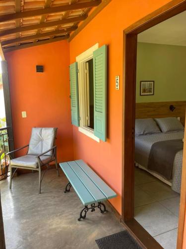 a room with a bed and a bench and a window at Pousada Villa Terracotta in Miguel Pereira