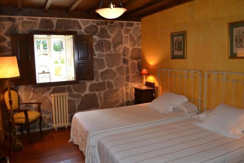 a bedroom with a bed and a stone wall at Palacio de Barreiro in Crecíente