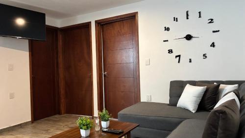 a living room with a couch and a clock on the wall at Bonito Departamento en Metepec