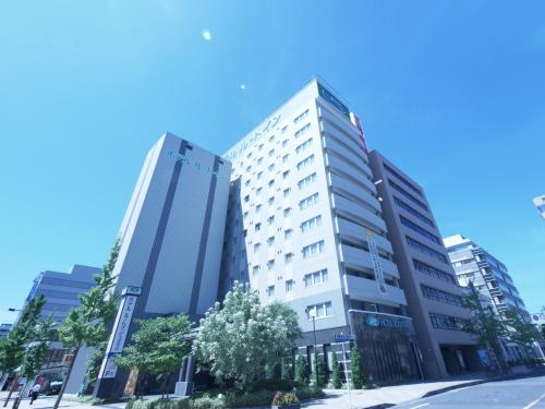 a tall white building on a city street at Hotel Route-Inn Saga Ekimae in Saga