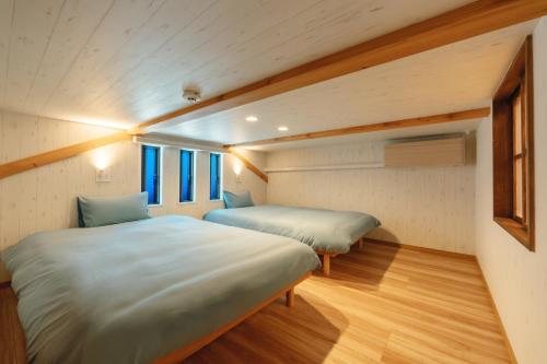 熊本YOUR ROOM treehouse KUMAMOTO - Vacation STAY 78979v的客房内设有两张床,铺有木地板,设有窗户。