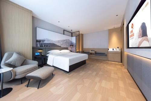a hotel room with a bed and a couch and chairs at 锦颐优选酒店呼和浩特巨海城国际会展中心店 in Hohhot