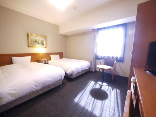 a hotel room with two beds and a window at Hotel Route-Inn Saga Ekimae in Saga
