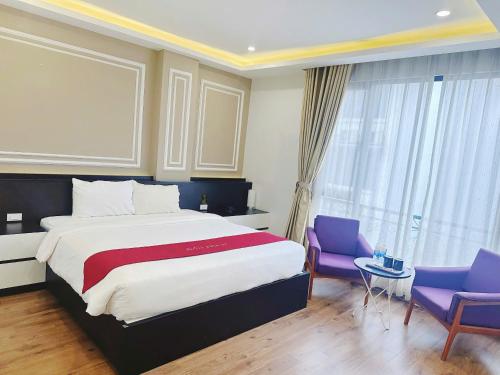 a bedroom with a large bed and two purple chairs at Hotel Villa Ju in Hanoi