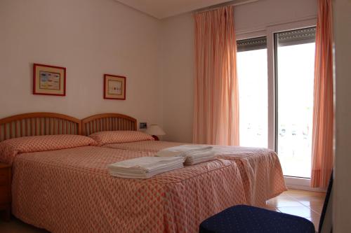 1 dormitorio con 1 cama con 2 toallas en Apartamentos Dominique, en La Manga del Mar Menor