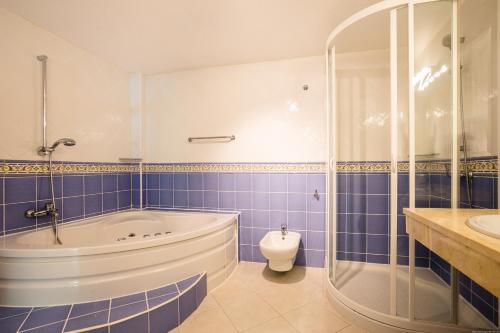 a blue tiled bathroom with a tub and a toilet at A 4 floors house with a large capacity in Los Cristianos