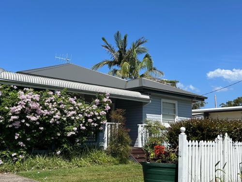 a house with a white fence and a palm tree at Spacious Stylish Coastal Escape in Tuncurry