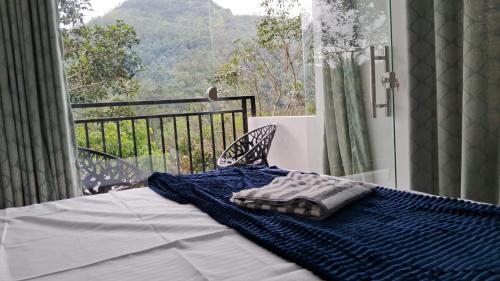 een bed met een blauwe deken erop op een balkon bij The Lovely Home Stay in Munnar