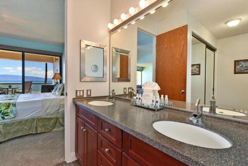 a bathroom with two sinks and a bedroom with a bed at Sands of Kahana 316 · SK 316 Spacious OceanFront 2BD w Ocean Vie in Kahana