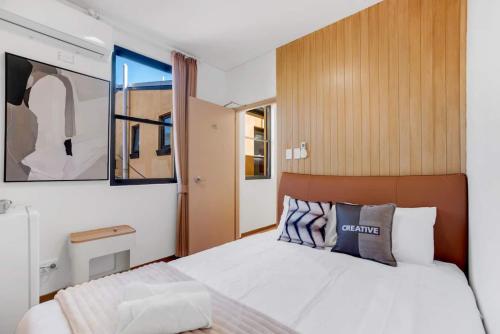 シドニーにあるVibrant Urban Lifestyle Private Room &Convenient locationの木製のヘッドボードが付いた白いベッドのある寝室