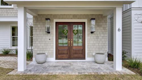 a house with a wooden door and two vases at 6 36th Avenue by AvantStay Stunning Private Pool in Isle of Palms