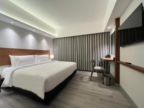 ジョグジャカルタにあるThe Jogja Hotel and Conference Centerの大きなベッドと机があるホテルの部屋