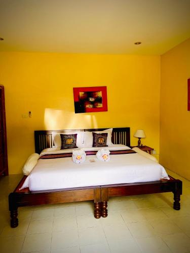 a bedroom with a large bed with yellow walls at Baan Ton Rak Boutique Resort in Ko Chang