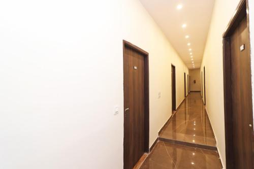 Un pasillo con paredes blancas y un pasillo con puertas de madera. en OYO 81074 Hotel Adb, en Faridabad