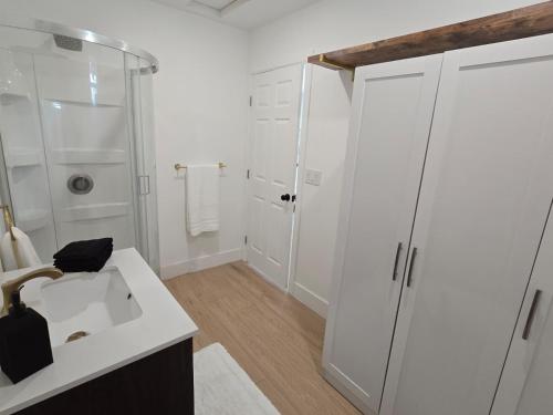 um banheiro branco com chuveiro e pia em Comfortable Luxury Studio em Northridge